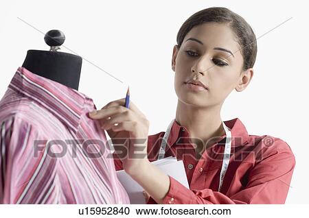 Stock Image - Close-up of a female fashion designer adjusting a shirt on a mannequin. Fotosearch