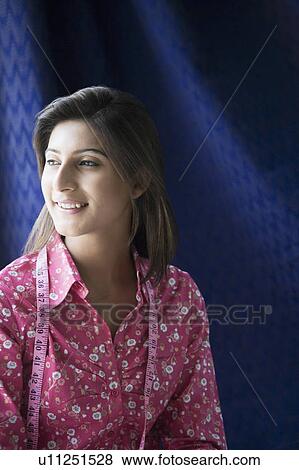 Stock Photo - Close-up of a female fashion designer smiling with a tape measure around her neck. Fotosearch