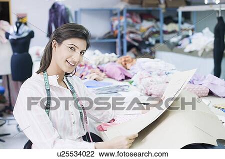 Portrait of a female fashion designer holding papers and smiling View Large Photo Image Stock Image - Portrait of a female fashion designer holding papers and smiling. Fotosearch