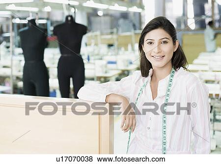 Portrait of a female fashion designer standing in a textile industry and smiling View Large Photo Image Stock Photo - Portrait of a female fashion designer standing in a textile industry and smiling. Fotosearch