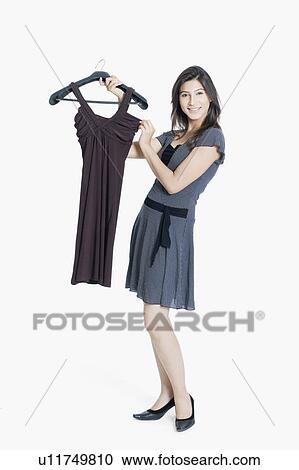 Stock Image - Portrait of a young woman holding a dress and smiling. Fotosearch