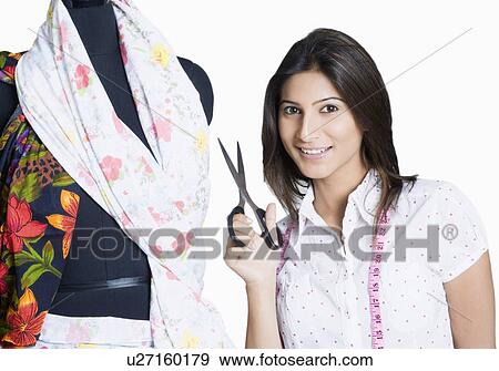 Portrait of a young woman standing beside a dressmakers model and smiling View Large Photo Image Stock Photo - Portrait of a young woman standing beside a dressmakers model and smiling. Fotosearch