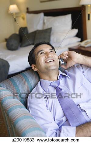 Businessman reclining in an armchair and using a mobile phone View Large Photo Image Stock Image - Businessman reclining in an armchair and using a mobile phone. Fotosearch