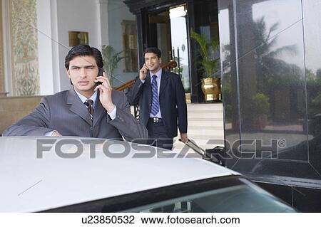 Businessman standing near a car and talking on a mobile phone View Large Photo Image Stock Image - Businessman standing near a car and talking on a mobile phone. Fotosearch