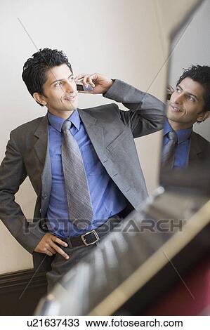 Stock Image - Businessman talking on a mobile phone and smiling. Fotosearch