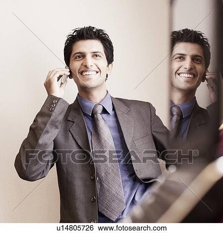 Businessman talking on a mobile phone and smiling View Large Photo Image Stock Photograph - Businessman talking on a mobile phone and smiling. Fotosearch