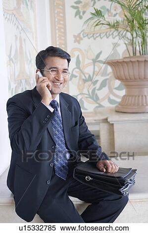 Businessman talking on a mobile phone and smiling View Large Photo Image Stock Photography - Businessman talking on a mobile phone and smiling. Fotosearch
