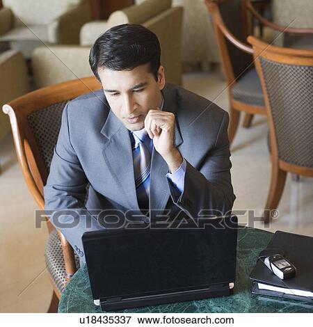 Businessman working on a laptop in a hotel View Large Photo Image Stock Photo - Businessman working on a laptop in a hotel. Fotosearch