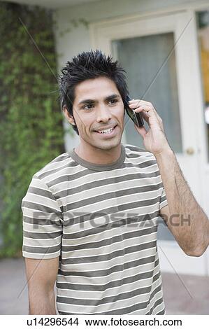 Close-up of a young man talking on a mobile phone and smiling View Large Photo Image Picture - Close-up of a young man talking on a mobile phone and smiling. Fotosearch