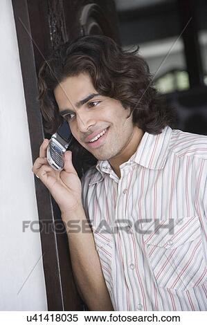 Close-up of a young man talking on a mobile phone View Large Photo Image Stock Photography - Close-up of a young man talking on a mobile phone. Fotosearch