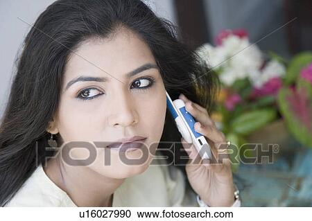 Close-up of a young woman talking on a mobile phone View Large Photo Image Stock Image - Close-up of a young woman talking on a mobile phone. Fotosearch