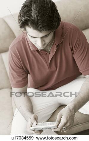High angle view of a young man using a mobile phone View Large Photo Image Stock Photo - High angle view of a young man using a mobile phone. Fotosearch