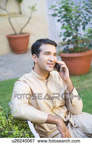 Mid adult man talking on a mobile phone and smiling View Large Photo Image Stock Photo - Mid adult man talking on a mobile phone and smiling. Fotosearch