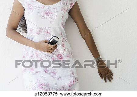 Mid section view of a woman holding a mobile phone View Large Photo Image Stock Photography - Mid section view of a woman holding a mobile phone. Fotosearch