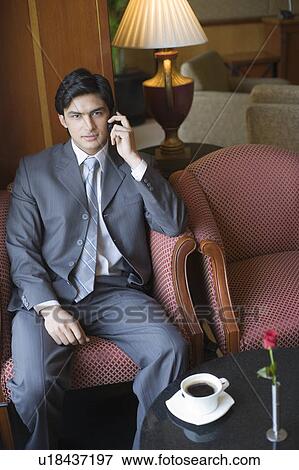 Portrait of a businessman sitting in an armchair and talking on a mobile phone View Large Photo Image Stock Photo - Portrait of a businessman sitting in an armchair and talking on a mobile phone. Fotosearch