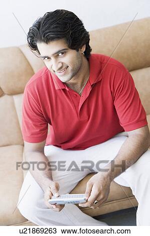 Stock Image - Portrait of a young man holding a mobile phone. Fotosearch