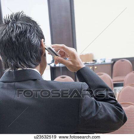 Rear view of a businessman talking on a mobile phone View Large Photo Image Stock Photo - Rear view of a businessman talking on a mobile phone. Fotosearch