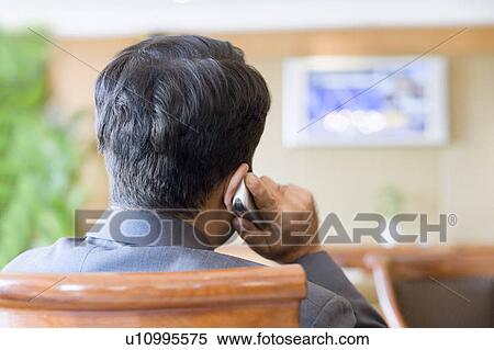 Rear view of a businessman talking on a mobile phone in a lobby View Large Photo Image Stock Photography - Rear view of a businessman talking on a mobile phone in a lobby. Fotosearch