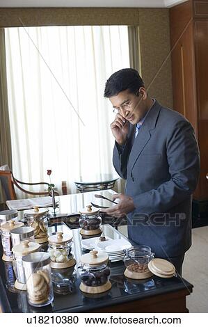 Stock Image - Side profile of a businessman talking on a mobile phone. Fotosearch