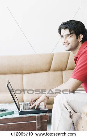 Side profile of a young man using a laptop View Large Photo Image Stock Image - Side profile of a young man using a laptop. Fotosearch