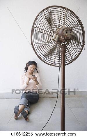 Young woman leaning against a wall and operating a mobile phone View Large Photo Image Stock Photography - Young woman leaning against a wall and operating a mobile phone. Fotosearch