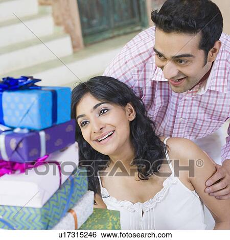 Stock Photograph - Close-up of a young couple looking at a stack of gifts. Fotosearch