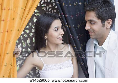 Close-up of a young woman smiling with a young man standing beside her View Large Photo Image Stock Photography - Close-up of a young woman smiling with a young man standing beside her. Fotosearch
