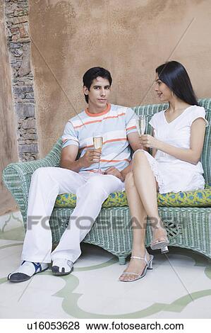 Portrait of a young couple sitting on a couch and holding champagne flutes View Large Photo Image Stock Photo - Portrait of a young couple sitting on a couch and holding champagne flutes. Fotosearch