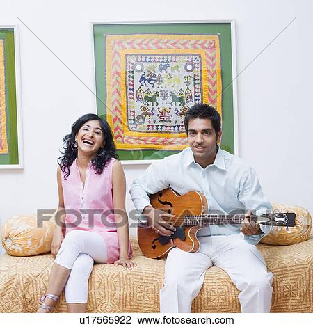 Portrait of a young man playing the guitar with a young woman sitting beside him View Large Photo Image Stock Image - Portrait of a young man playing the guitar with a young woman sitting beside him. Fotosearch