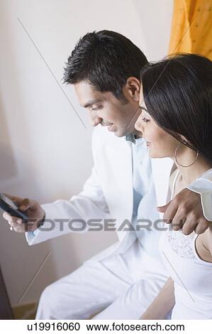 Side profile of a young man using a mobile phone with a young woman sitting beside him View Large Photo Image Stock Image - Side profile of a young man using a mobile phone with a young woman sitting beside him. Fotosearch