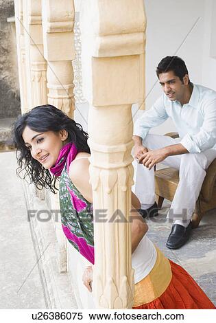 Side profile of a young woman leaning against a column with a young man sitting behind her View Large Photo Image Stock Photography - Side profile of a young woman leaning against a column with a young man sitting behind her. Fotosearch