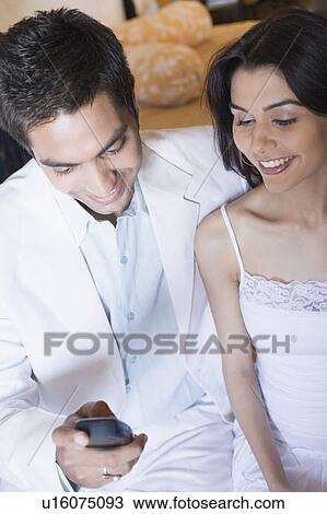 Young couple looking at a mobile phone and smiling View Large Photo Image Stock Image - Young couple looking at a mobile phone and smiling. Fotosearch