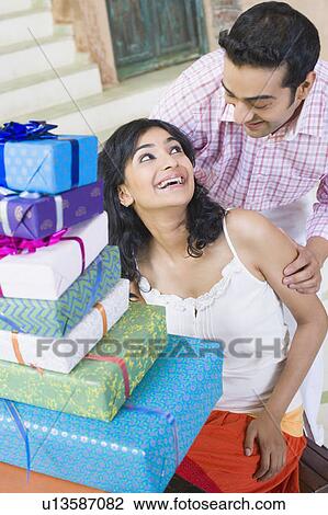 Young couple looking at each other with a stack of gifts in front of them View Large Photo Image Stock Image - Young couple looking at each other with a stack of gifts in front of them. Fotosearch