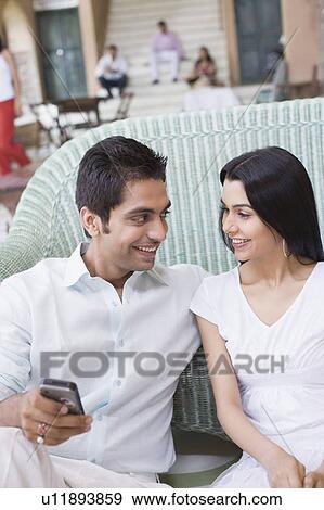 Young couple sitting on a couch and smiling View Large Photo Image Stock Photo - Young couple sitting on a couch and smiling. Fotosearch