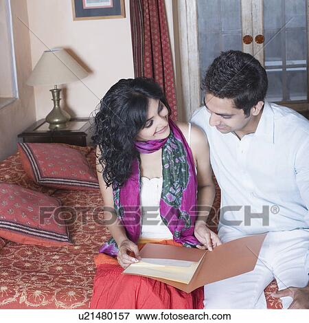 Young couple sitting on the bed with a young woman holding a file View Large Photo Image Stock Photo - Young couple sitting on the bed with a young woman holding a file. Fotosearch