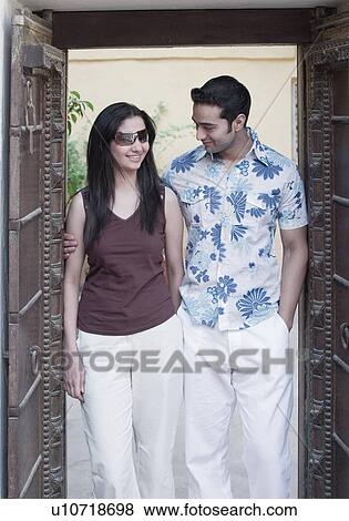 Stock Photo - Young man standing with his arm around a young woman. Fotosearch