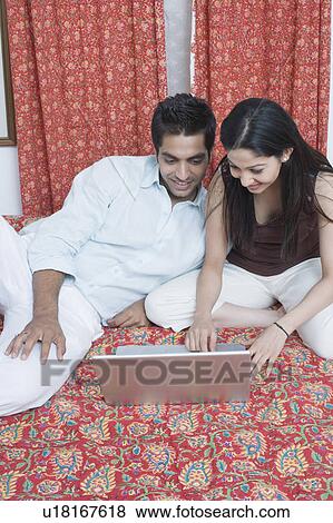 Young woman sitting on the bed and using a laptop View Large Photo Image Stock Photo - Young woman sitting on the bed and using a laptop. Fotosearch