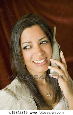 Close-up of a young woman talking on a cordless phone View Large Photo Image Stock Photograph - Close-up of a young woman talking on a cordless phone. Fotosearch