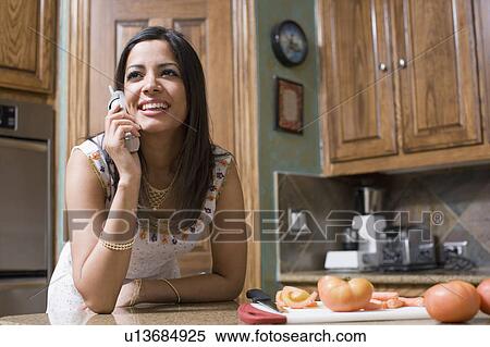 Close-up of a young woman talking on a cordless phone in a kitchen View Large Photo Image Stock Photography - Close-up of a young woman talking on a cordless phone in a kitchen. Fotosearch