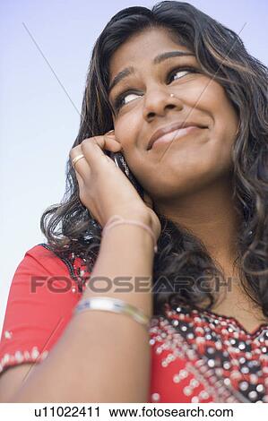 Stock Image - Low angle view of a young woman talking on a mobile phone. Fotosearch