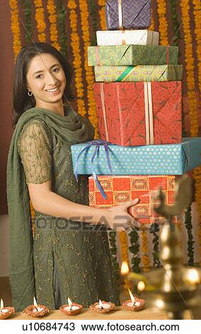 Portrait of a young woman holding a stack of diwali gifts and smiling View Large Photo Image Stock Image - Portrait of a young woman holding a stack of diwali gifts and smiling. Fotosearch