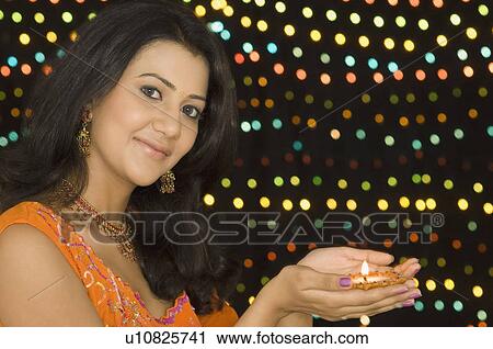 Portrait of a young woman holding a diwali lamp View Large Photo Image Stock Image - Portrait of a young woman holding a diwali lamp. Fotosearch