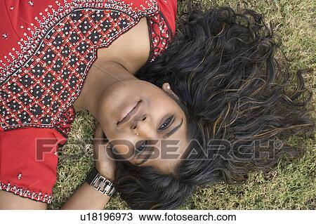 Portrait of a young woman lying on the grass View Large Photo Image Stock Image - Portrait of a young woman lying on the grass. Fotosearch