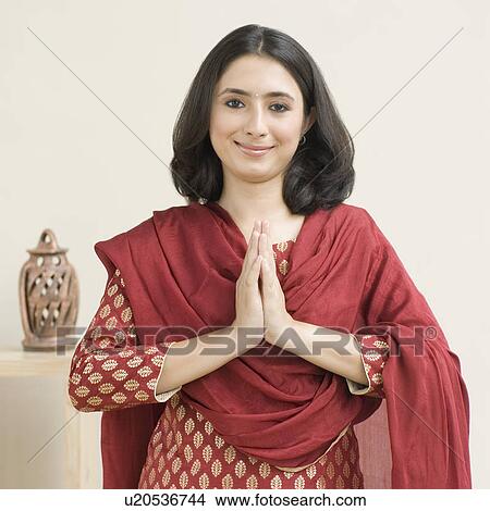 Picture - Portrait of a young woman standing in prayer position and smiling. Fotosearch