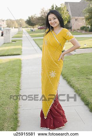 Portrait of a young woman standing with her hand on her hip and smiling View Large Photo Image Stock Image - Portrait of a young woman standing with her hand on her hip and smiling. Fotosearch