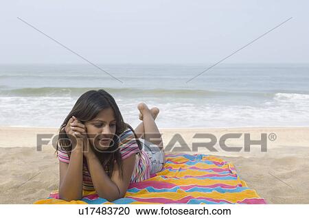 Stock Image - Young woman lying on the beach and smiling. Fotosearch