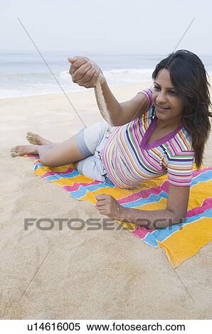 Stock Photography - Young woman playing with sand on the beach. Fotosearch