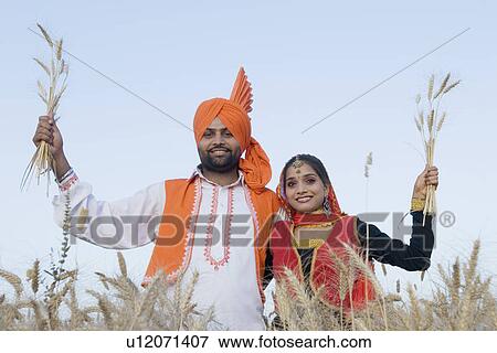 Portrait of a young couple standing in a wheat field and holding crop View Large Photo Image Stock Photo - Portrait of a young couple standing in a wheat field and holding crop. Fotosearch