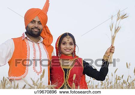 Portrait of a young couple standing in a wheat field and holding crop View Large Photo Image Stock Photograph - Portrait of a young couple standing in a wheat field and holding crop. Fotosearch