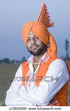 Stock Image - Portrait of a young man standing in a wheat field. Fotosearch